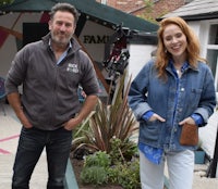 a man and a woman standing in front of a house